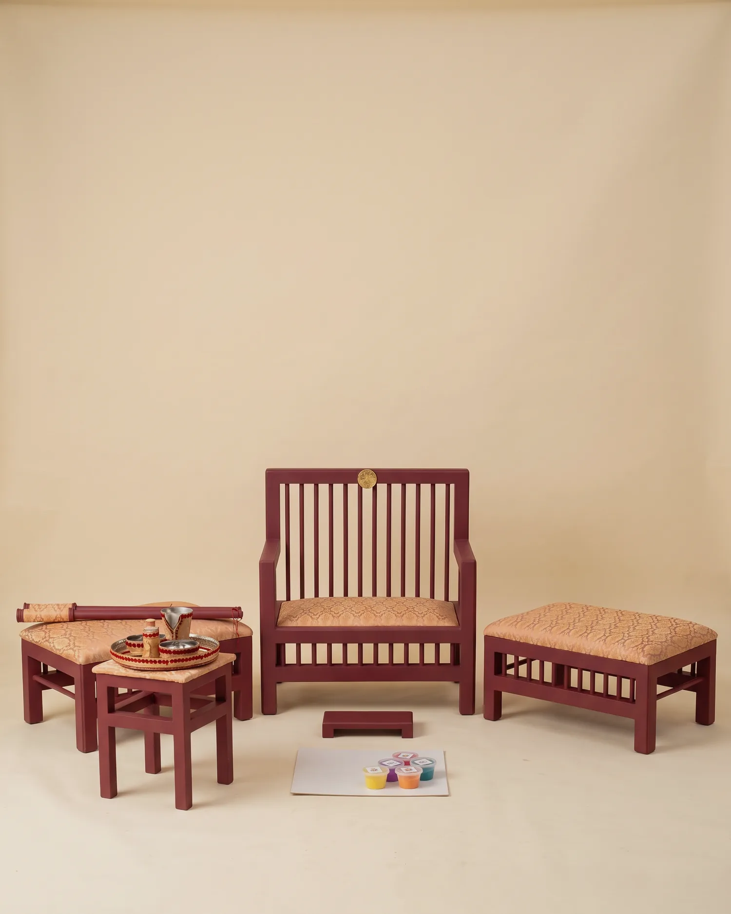 The Peaches & Wine Maiyan suite on a warm ivory studio backdrop: deep wine slatted frames with peach and gold brocade seats, the head chair between two benches, with the tray table and Sagan tray alongside.