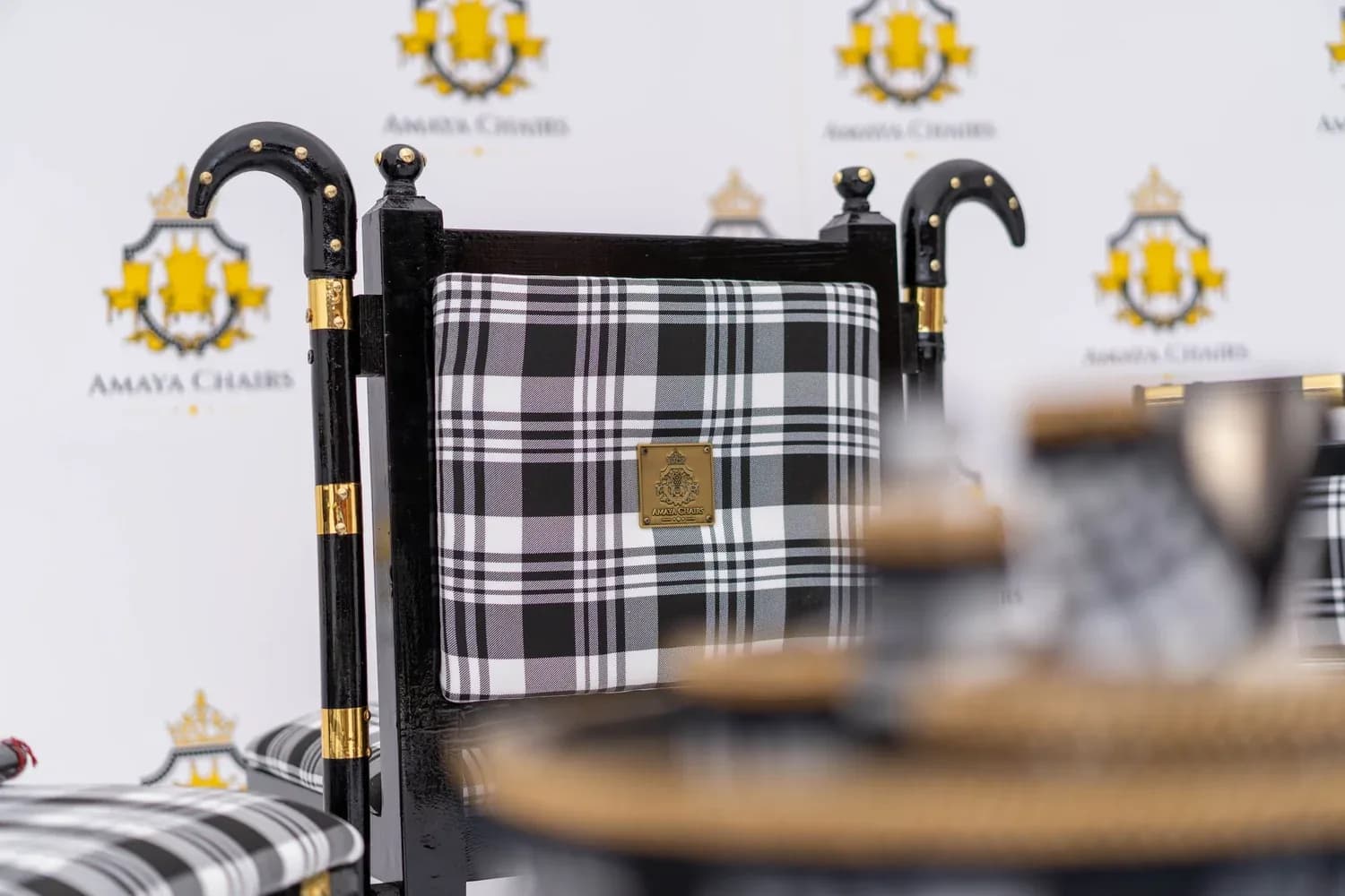 Detail of a Gabru chair back, showing the curved khunda-style finial above the black-and-white check upholstery.